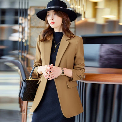 Donna elegante con cappotto marrone e cappello nero, in un ambiente moderno. Moda autunnale, stile sofisticato, abbigliamento femminile di tendenza.