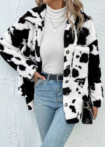 Giacca in pelliccia sintetica bianca e nera con motivo mucca, indossata su dolcevita bianco e jeans. Stile moda autunno inverno donna.