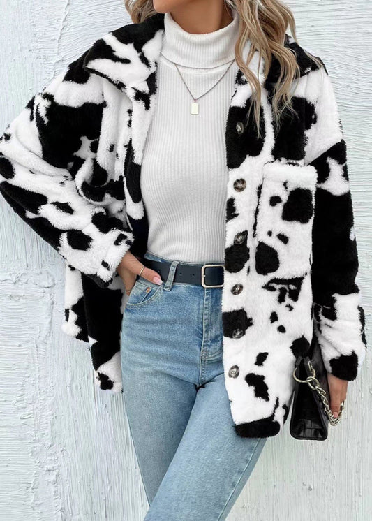 Giacca in pelliccia sintetica bianca e nera con motivo mucca, indossata su dolcevita bianco e jeans. Stile moda autunno inverno donna.