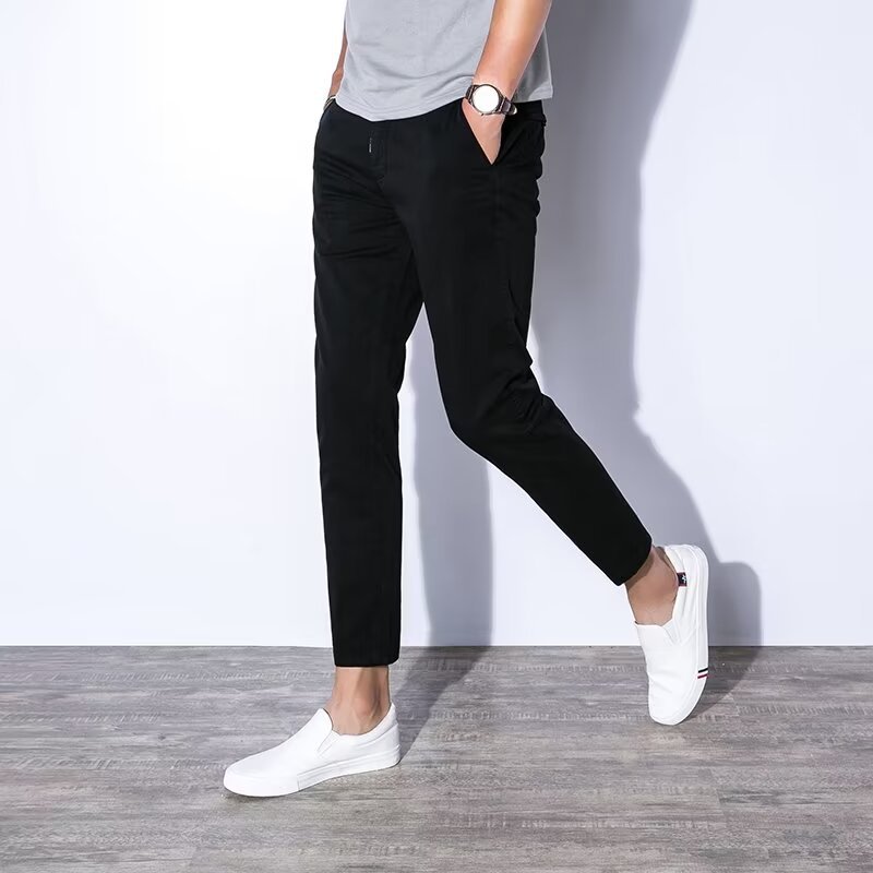 Uomo in pantaloni neri e scarpe bianche, cammina su pavimento in legno. Moda casual maschile, abbigliamento moderno, stile urbano.