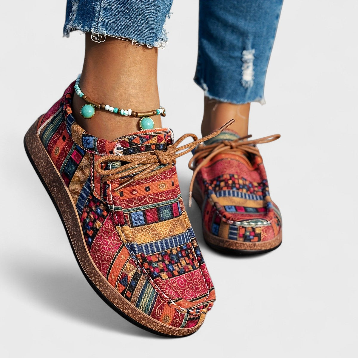 Scarpe colorate in tessuto etnico con lacci, indossate con jeans strappati. Design vivace e dettagli unici, perfette per uno stile casual e boho.