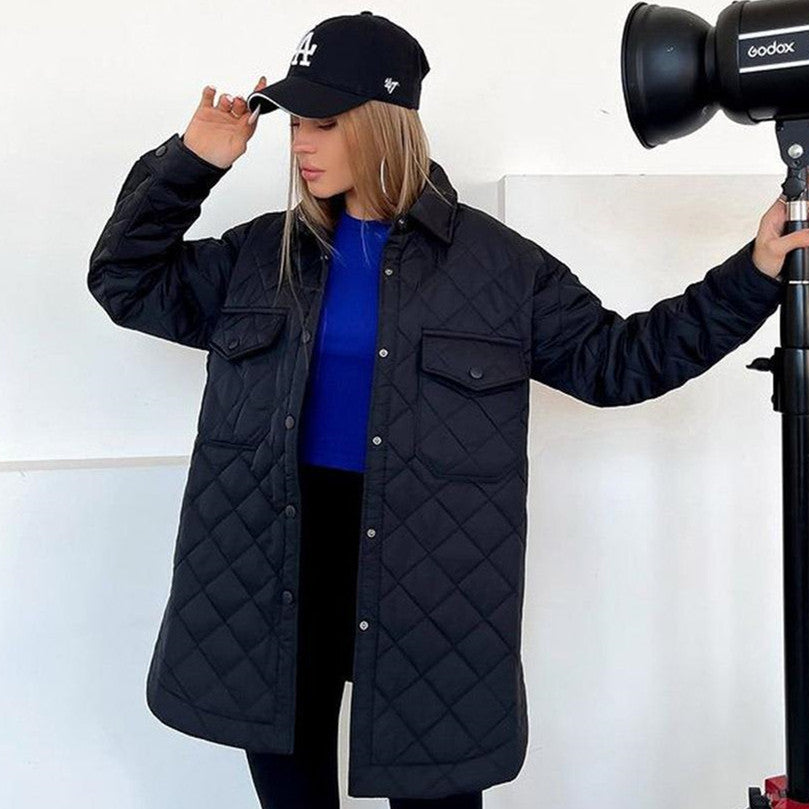 Donna con cappotto trapuntato nero, cappello da baseball nero, e maglia blu. Moda autunnale, abbigliamento casual, stile urbano.