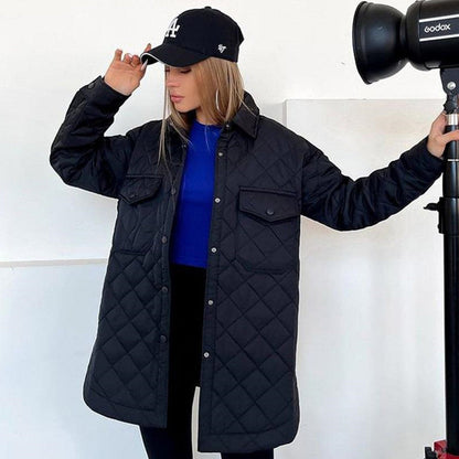 Donna con cappotto trapuntato nero, cappello da baseball nero, e maglia blu. Moda autunnale, abbigliamento casual, stile urbano.