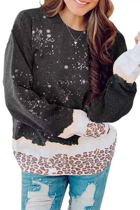 Donna con maglione nero a macchie bianche e dettagli leopardati, jeans strappati. Moda casual autunnale, abbigliamento femminile trendy.
