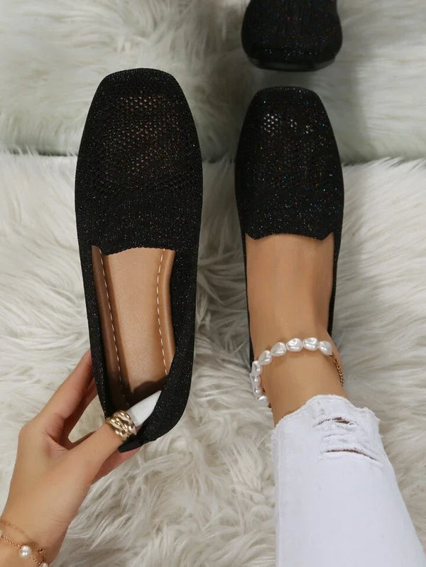 Scarpe da donna nere eleganti, tessuto scintillante, su tappeto bianco. Moda calzature femminili, stile casual chic, comfort quotidiano.