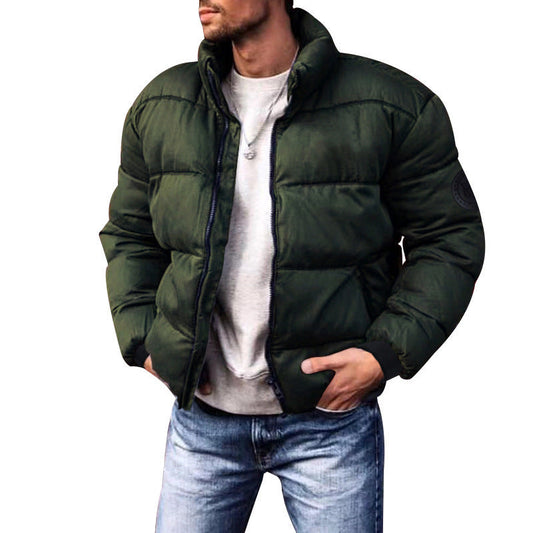 Giacca invernale verde scuro imbottita, uomo, stile casual, con zip, indossata su maglia grigia e jeans. Moda maschile, abbigliamento caldo.