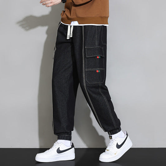 Pantaloni cargo neri da uomo con tasche laterali, dettagli bianchi e sneakers bianche Nike. Stile casual, moda streetwear.
