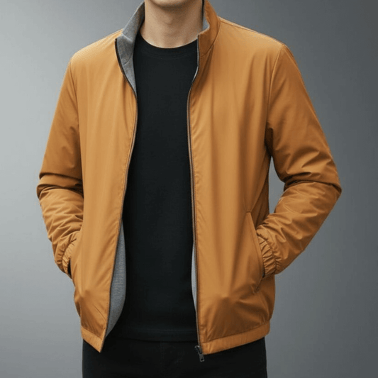 Giacca uomo marrone chiaro, stile casual, con zip frontale e tasche laterali, indossata su maglia nera. Moda maschile autunnale elegante.