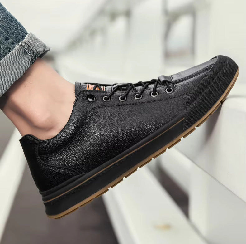 Scarpa da ginnastica nera in pelle, suola in gomma marrone, indossata con jeans. Design casual ed elegante, perfetta per moda urbana e comfort.