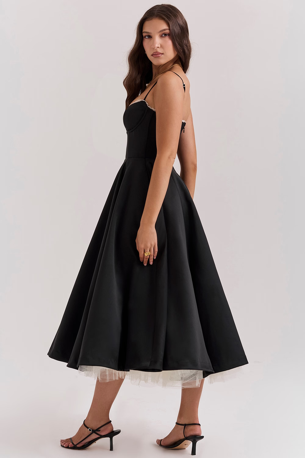 Donna in abito nero elegante, lunghezza media, con spalline sottili e gonna ampia. Moda femminile, abbigliamento da sera, stile sofisticato.