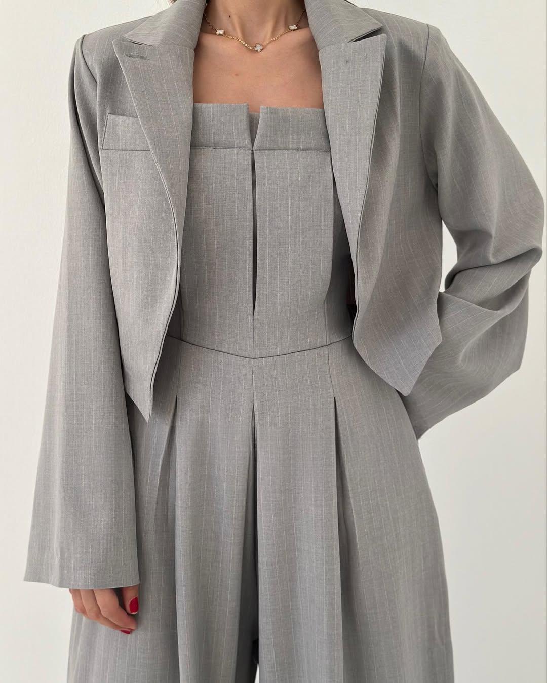 Completo elegante grigio da donna, giacca e pantaloni a vita alta, tessuto a righe sottili, moda formale, abbigliamento da ufficio.