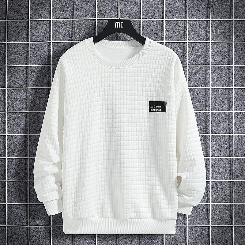 Felpa bianca trapuntata su gruccia nera, sfondo a griglia grigia. Design minimalista, etichetta nera sul petto. Moda casual, abbigliamento uomo.