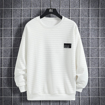 Felpa bianca trapuntata su gruccia nera, sfondo a griglia grigia. Design minimalista, etichetta nera sul petto. Moda casual, abbigliamento uomo.