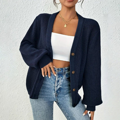 Donna con cardigan blu scuro a maglia grossa, top bianco e jeans. Moda casual autunnale, stile elegante, abbigliamento femminile trendy.