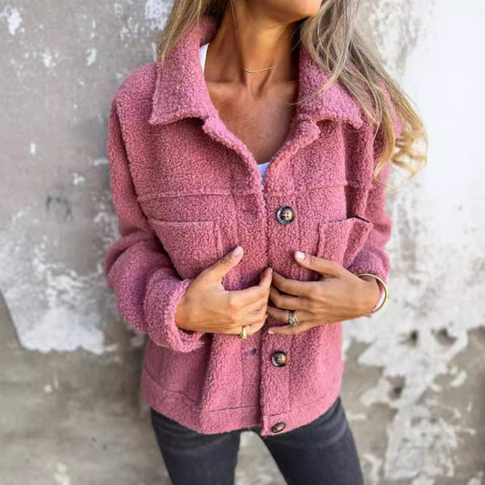 Giacca in pile rosa donna, stile casual, con bottoni, indossata su sfondo muro grigio. Moda autunnale, abbigliamento caldo e confortevole.