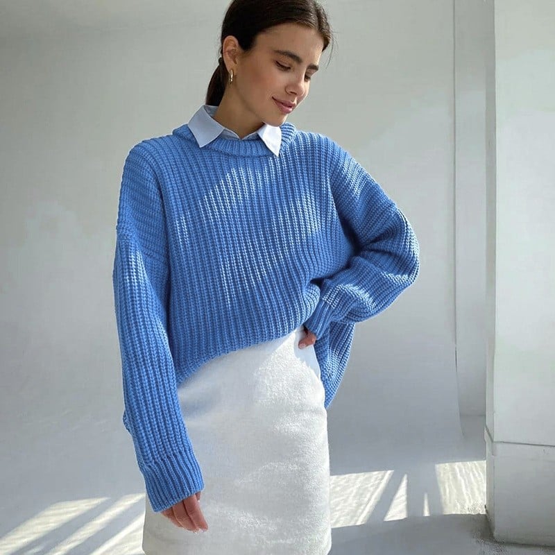 Donna con maglione blu oversize e camicia bianca, posa in uno spazio luminoso. Moda autunnale, abbigliamento casual chic, tendenze 2023.
