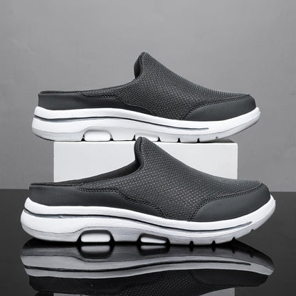 Scarpe slip-on nere da uomo su sfondo grigio, design sportivo con suola bianca ammortizzata, tessuto traspirante, moda casual e comfort.