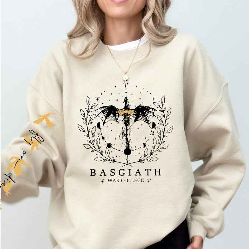 Donna con felpa beige con stampa drago nero e scritta "BASGIATH WAR COLLEGE". Design fantasy, moda casual, abbigliamento autunno.