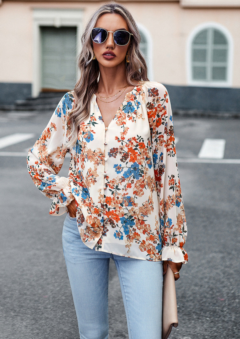 Donna con occhiali da sole indossa camicetta floreale colorata e jeans chiari, posa all'aperto. Moda femminile, stile casual chic, abbigliamento estivo.