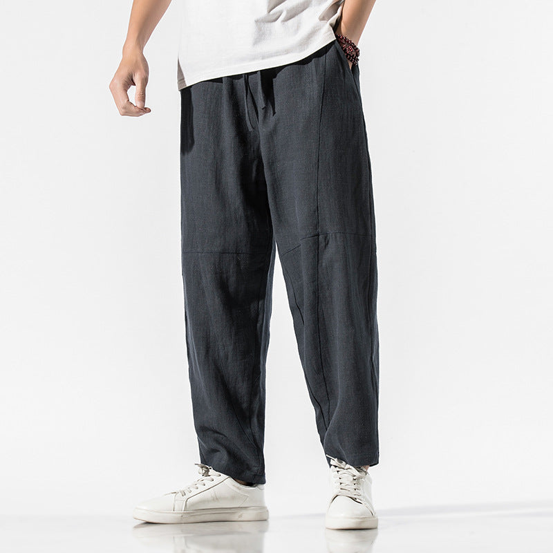 Pantaloni larghi uomo in lino nero, stile casual, abbinati a scarpe bianche. Moda maschile estiva, abbigliamento comodo e traspirante.