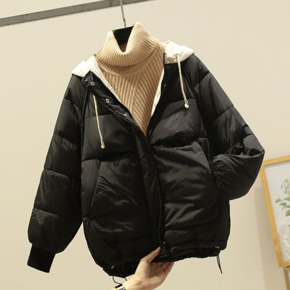Giacca invernale nera imbottita con cappuccio bianco, chiusura a zip, e collo alto beige. Moda donna, abbigliamento caldo, stile casual.