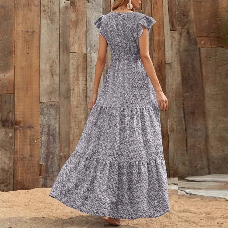 Donna con abito lungo floreale grigio, sfondo di legno rustico. Moda estiva, abbigliamento casual elegante, tendenza abiti lunghi 2023.