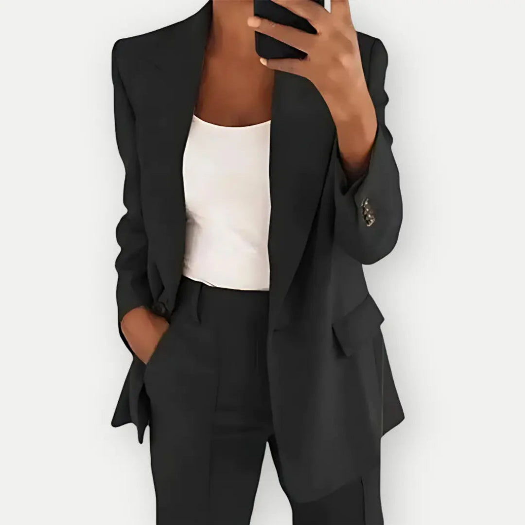 Donna in abito elegante nero, giacca e pantaloni, con top bianco, scatta selfie. Moda business casual, outfit professionale, stile moderno.
