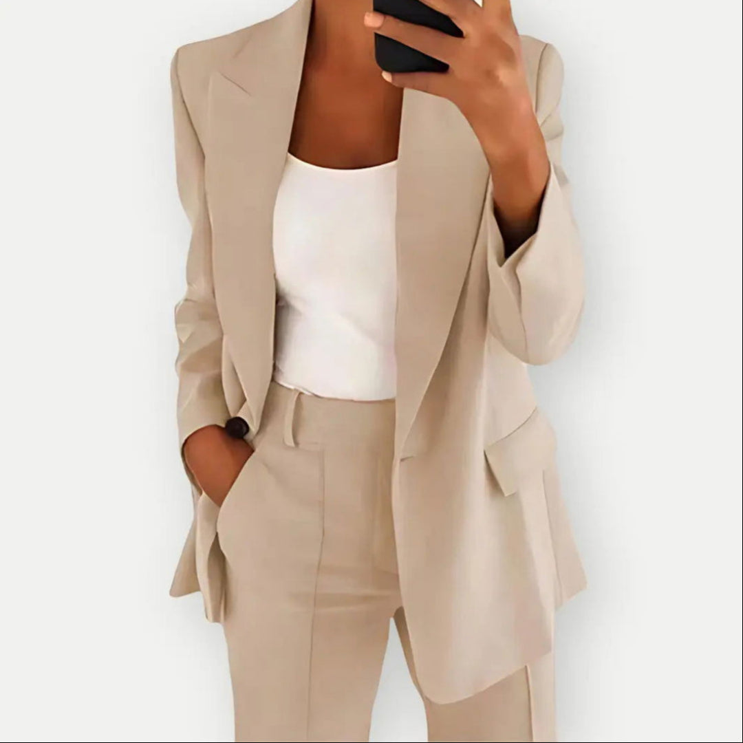 Donna in abito elegante beige, giacca e pantaloni coordinati, con top bianco. Moda business casual, stile professionale, tendenza abbigliamento 2023.