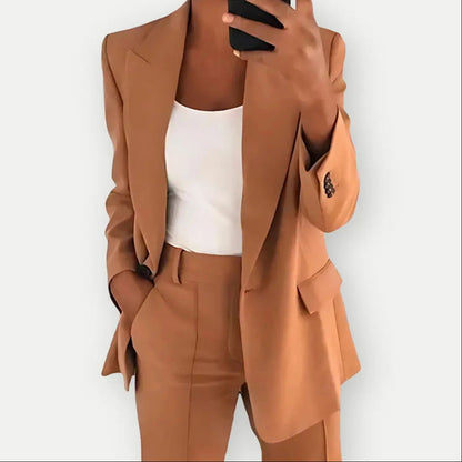 Donna in abito elegante marrone, giacca e pantaloni coordinati, con top bianco. Moda business casual, outfit professionale, stile moderno.
