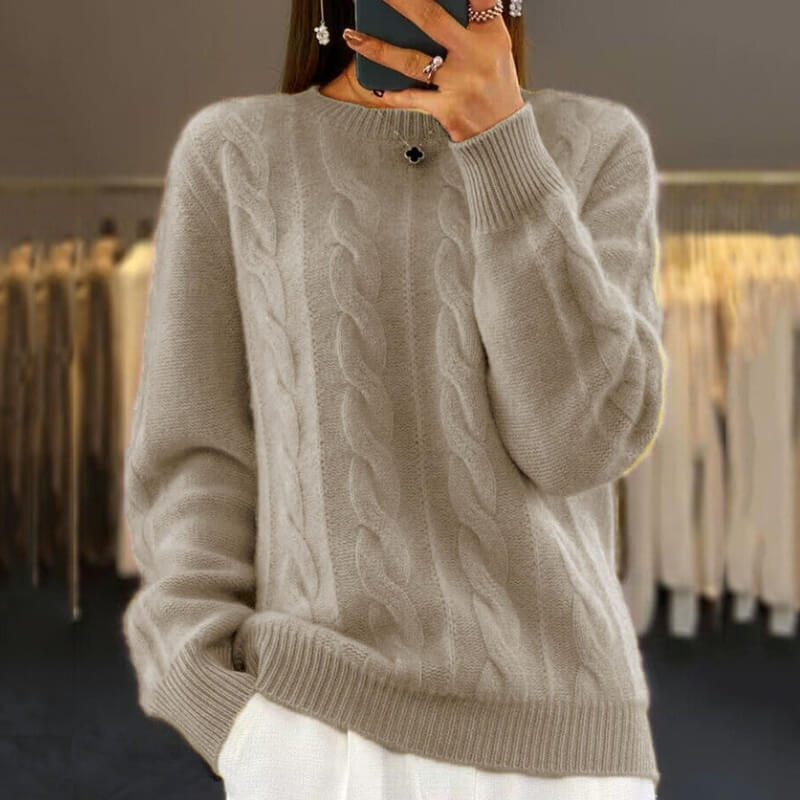 Maglione beige a trecce in lana, indossato da una persona che scatta una foto allo specchio in un negozio di abbigliamento.