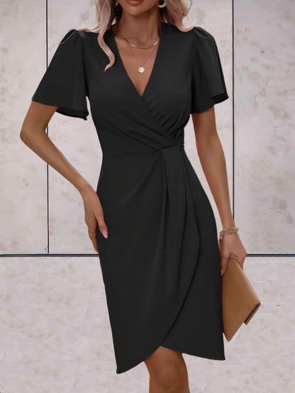 Abito nero elegante da donna con scollo a V e maniche corte, indossato con accessori dorati e pochette beige. Moda femminile, abbigliamento chic.