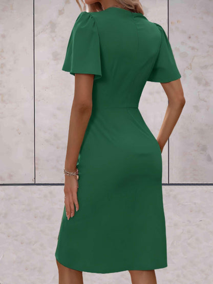 Abito verde elegante da donna, maniche corte, lunghezza al ginocchio, sfondo marmo chiaro. Moda femminile, abbigliamento chic, stile sofisticato.