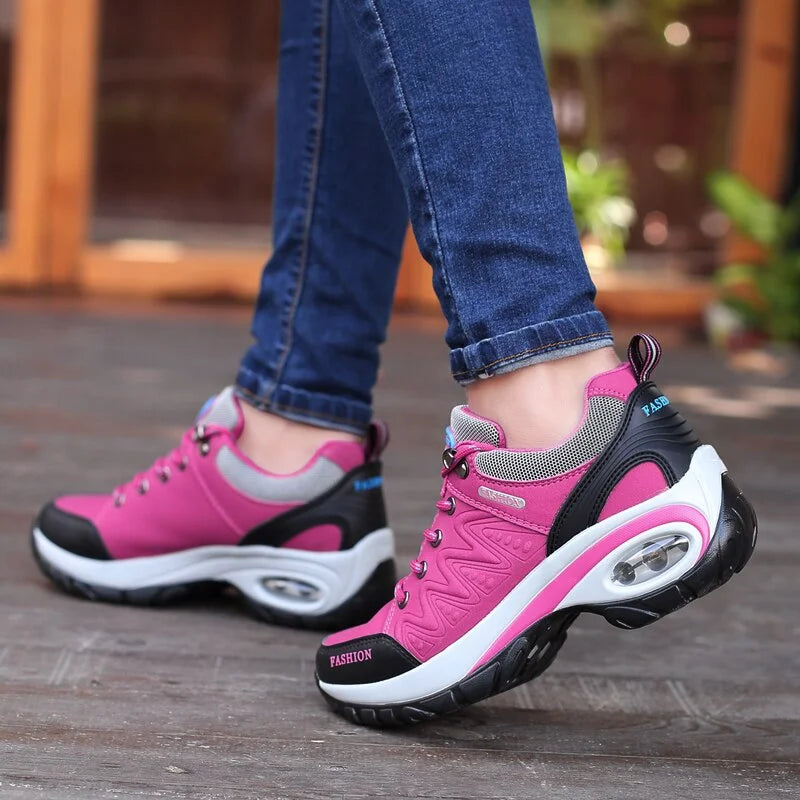 Scarpe da ginnastica rosa e nere da donna, suola ammortizzata, indossate con jeans. Scarpe sportive alla moda per attività all'aperto.
