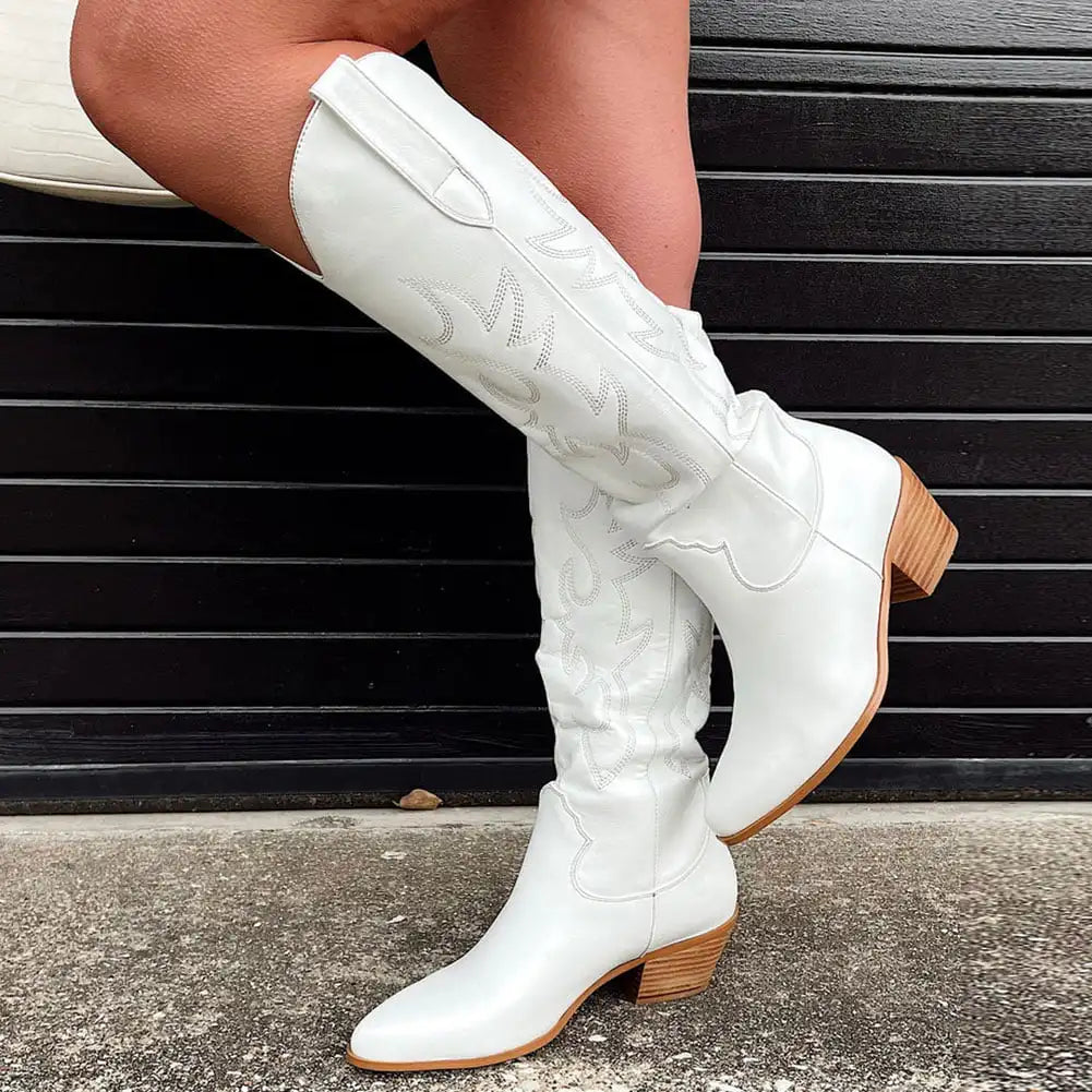 Stivali texani bianchi da donna con tacco in legno, dettagli ricamati, su sfondo nero. Moda autunnale, calzature eleganti e trendy.