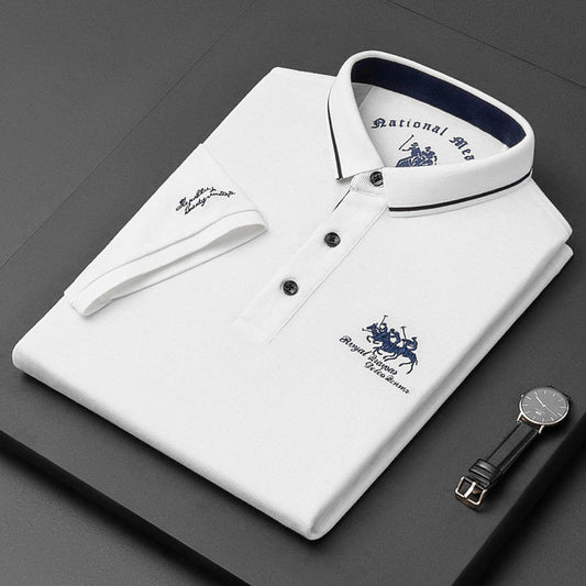 Camicia polo bianca piegata con colletto blu, logo ricamato, orologio nero e cinturino in pelle su sfondo nero. Elegante abbigliamento maschile.
