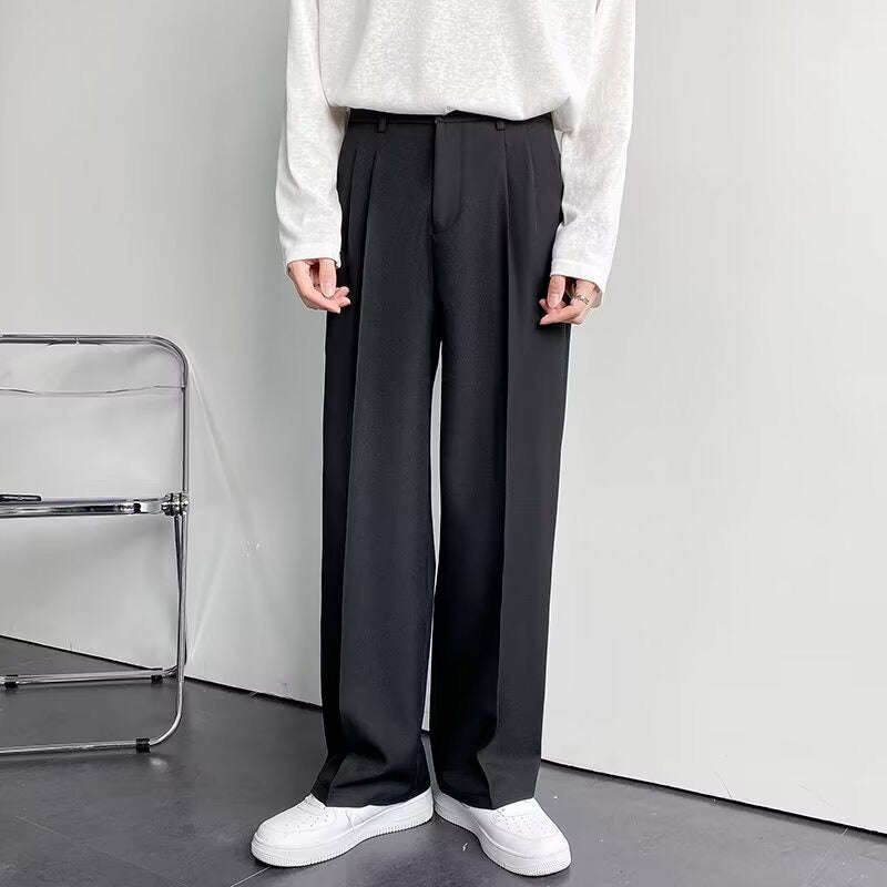 Pantaloni neri eleganti da uomo, taglio dritto, abbinati a maglia bianca e scarpe sportive bianche. Moda maschile casual chic.