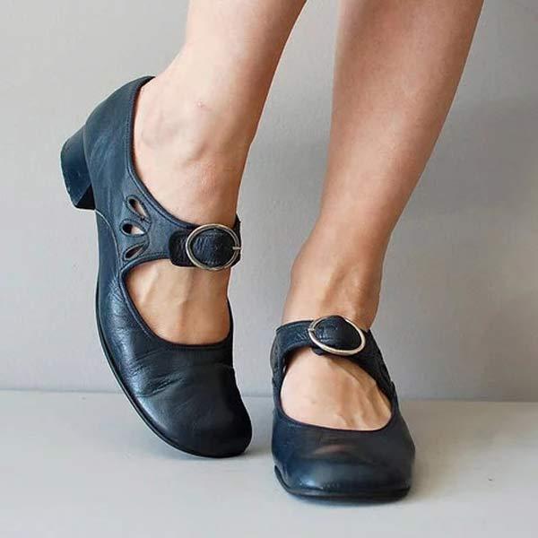 Scarpe Mary Jane nere in pelle con cinturino e tacco basso, indossate su pavimento grigio. Scarpe eleganti e comode per donna.