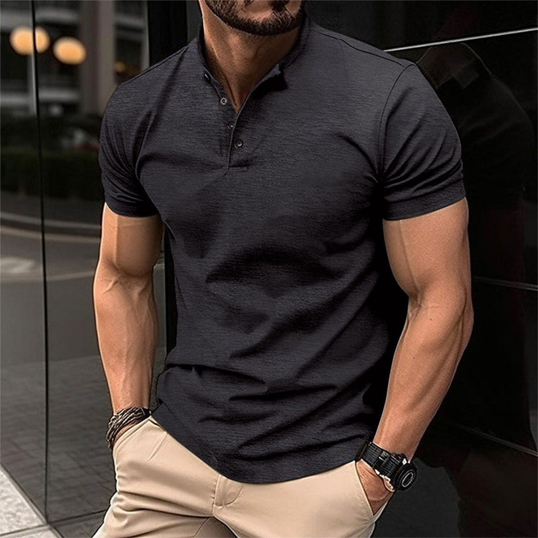 Uomo muscoloso in polo nera e pantaloni beige, orologio al polso, posa in strada urbana. Moda maschile casual, stile moderno.