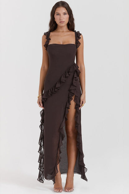 Abito lungo elegante marrone con volant, spacco laterale e scollatura quadrata, indossato da modella su sfondo bianco. Moda femminile sofisticata.