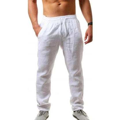 Uomo in pantaloni di lino bianchi, elastico in vita, mani in tasca, scarpe sportive grigie. Moda estiva casual maschile.