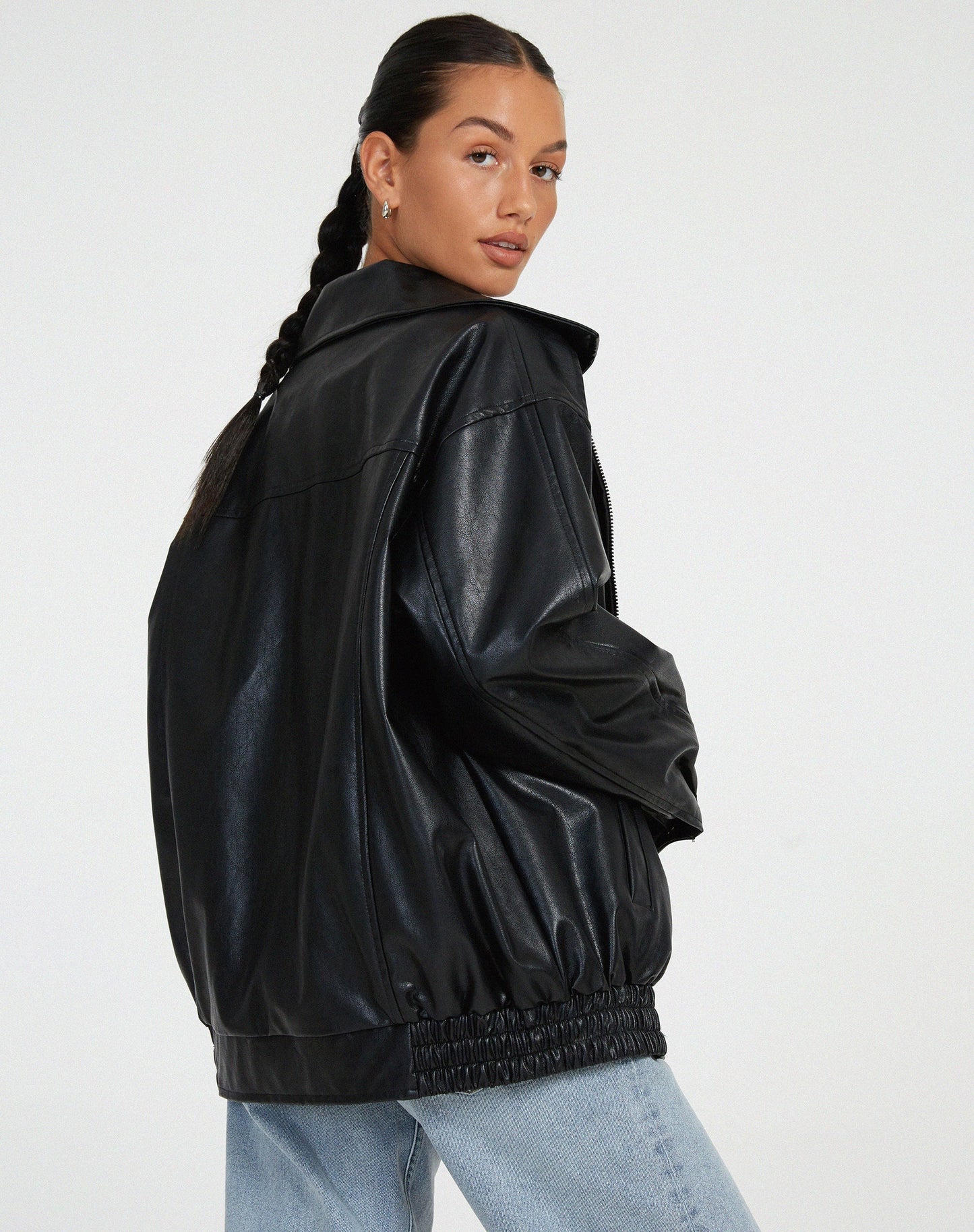 Donna con giacca in pelle nera oversize e jeans chiari, stile casual chic. Moda autunnale, tendenze abbigliamento donna 2023.
