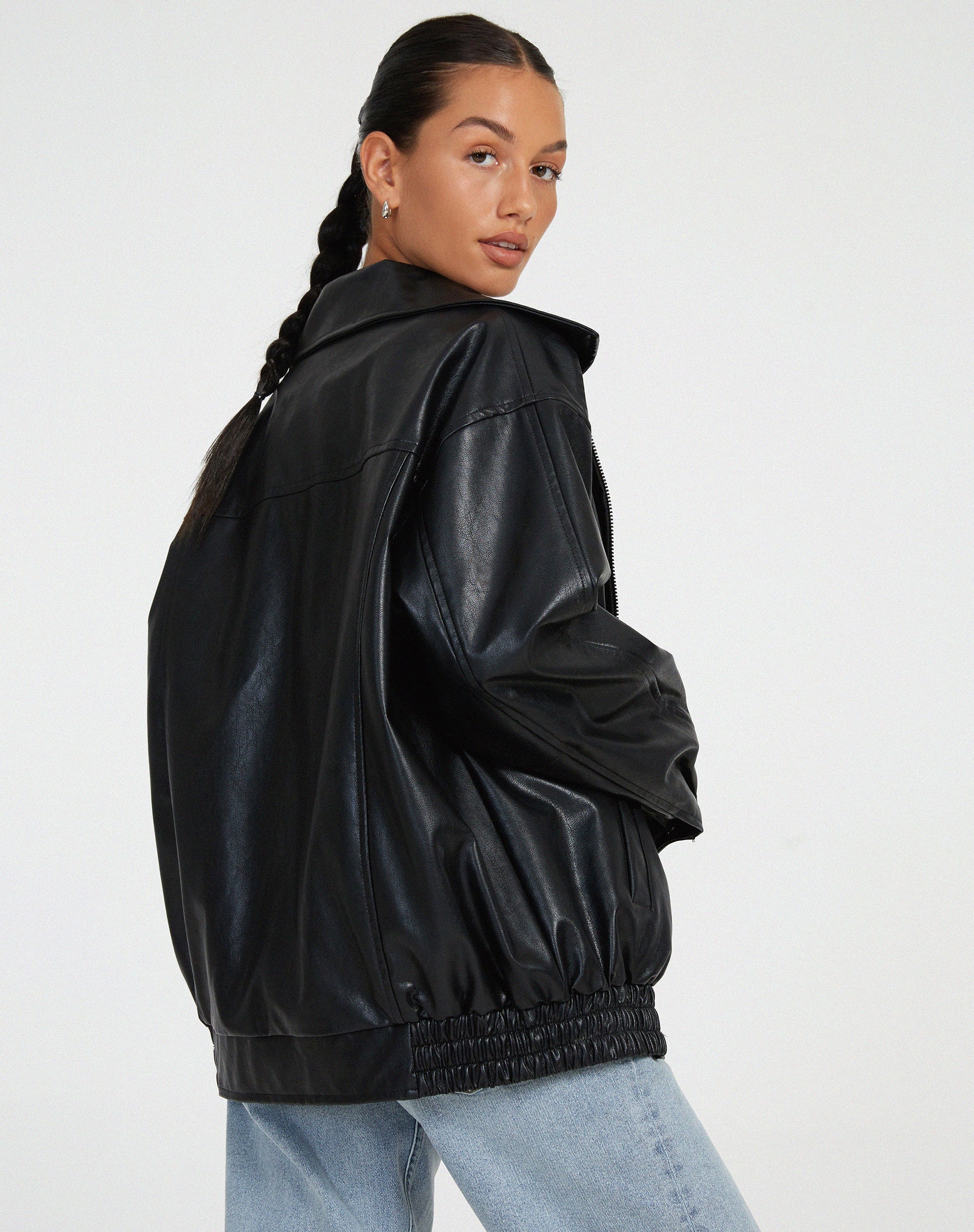 Donna con giacca in pelle nera oversize e jeans chiari, stile casual chic. Moda autunnale, tendenze abbigliamento donna 2023.