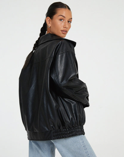 Donna con giacca in pelle nera oversize e jeans chiari, stile casual chic. Moda autunnale, tendenze abbigliamento donna 2023.