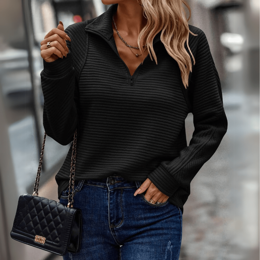 Donna con maglione nero a coste, jeans blu e borsa a tracolla trapuntata nera. Moda autunnale, stile casual chic, abbigliamento femminile elegante.