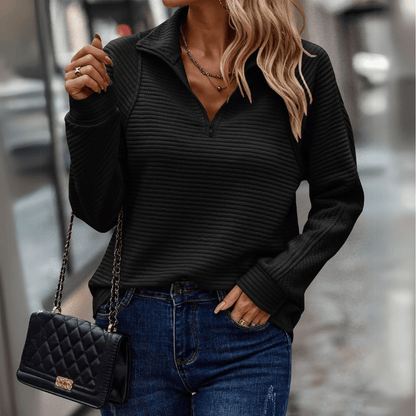 Donna con maglione nero a coste, jeans blu e borsa a tracolla trapuntata nera. Moda autunnale, stile casual chic, abbigliamento femminile elegante.
