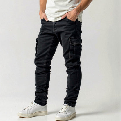 Jeans cargo neri da uomo con tasche laterali, abbinati a scarpe da ginnastica bianche e maglietta bianca. Moda casual maschile moderna.
