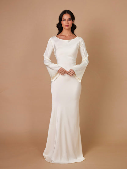 Donna in abito da sposa bianco elegante, maniche lunghe svasate, sfondo beige. Moda nuziale, abito da cerimonia, stile classico.