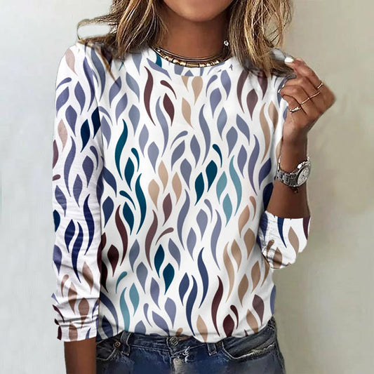 Donna con maglia a maniche lunghe con motivo astratto a foglie multicolore, indossa jeans e orologio. Moda casual autunnale, stile moderno.