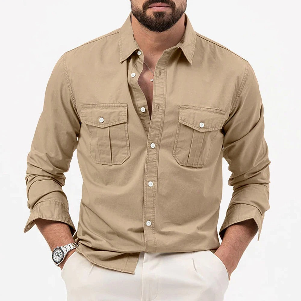 Camicia beige da uomo con tasche frontali, maniche lunghe, abbinata a pantaloni bianchi. Stile casual elegante, moda maschile contemporanea.