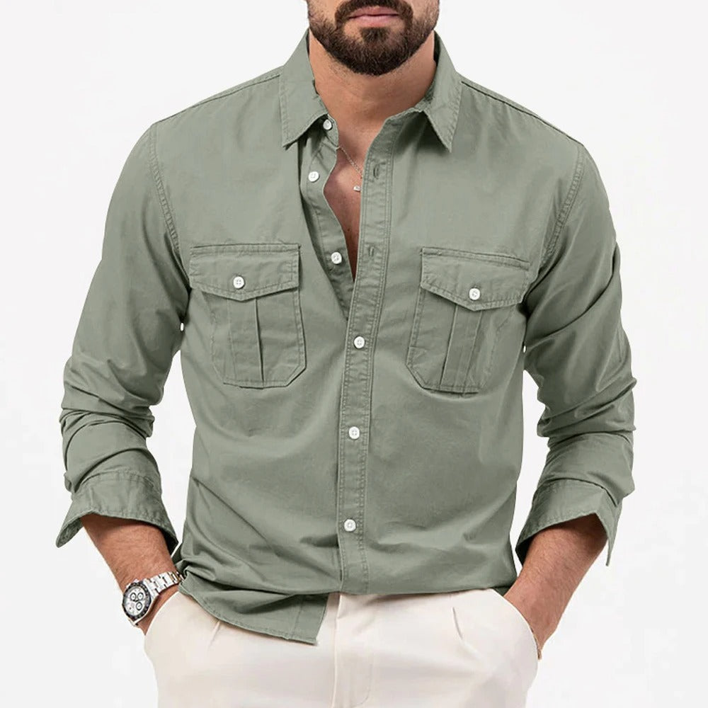 Camicia verde militare da uomo con tasche frontali, maniche lunghe e bottoni, indossata con pantaloni chiari. Stile casual elegante.